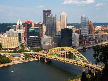 Pittsburgh, Pennsylvania, ABD - 8 Ağustos 2023: Şehir silueti modern binalar ve nehir üzerinde canlı sarı bir köprü sergiliyor.