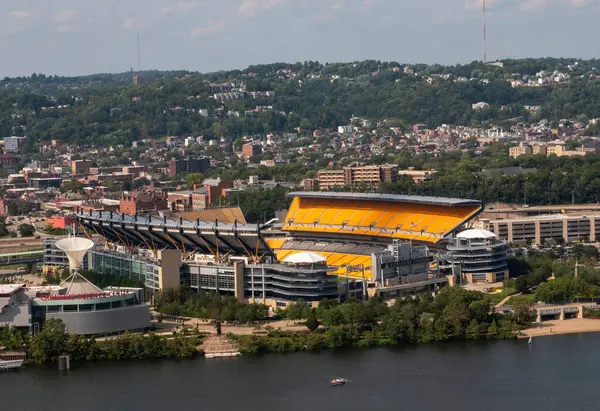Pittsburgh, Pennsylvania, ABD - 8 Ağustos 2023: Nehir kıyısında canlı koltuklar ve şehrin ufuk çizgisi sergilenen parlak bir stadyum.