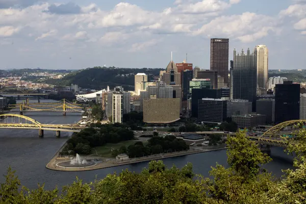 Pittsburgh, Pennsylvania, ABD - 8 Ağustos 2023: Pittsburgh şehir manzarasında mavi gökyüzü altında köprüler ve yeşil Point State parkları yer alıyor.