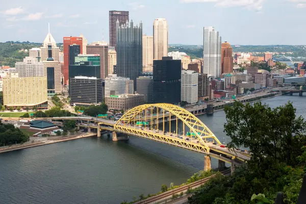 Pittsburgh, Pennsylvania, ABD - 8 Ağustos 2023: Pittsburgh silueti, canlı sarı bir köprünün yanında modern binalar sergiliyor.