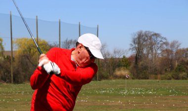 Kırmızılı golfçü açık havada golf sahasında yumruk sallıyor..