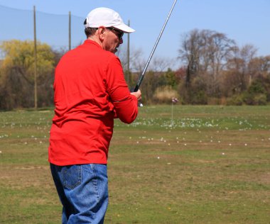 Golfçü açık mavi gökyüzünün altında atış talimi yapıyor..