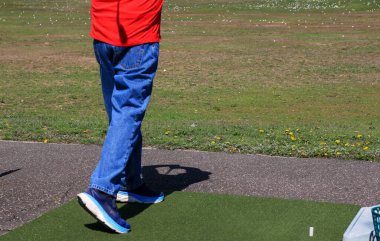 Oyuncu golf salıncağını antrenman sahasında güneşlenirken yapar..