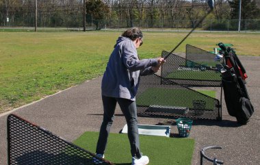 Bir golfçü gün ortasında golf sahasında atış yapar ve becerilerini geliştirir..