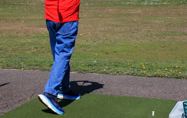 Oyuncu golf salıncağını antrenman sahasında güneşlenirken yapar..