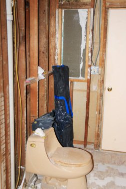 Bitmemiş banyo çıplak duvarları, tesisatı ve yenileme malzemelerini gösteriyor..