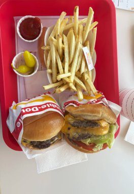 Summerville, Nevada, ABD - 8 Haziran 2025: Altın kızartma ve baharatların yanında iki lezzetli burger.