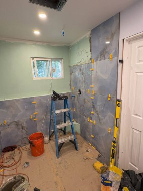 İşçiler modern bir banyonun duvarlarına büyük fayanslar yerleştiriyorlar..