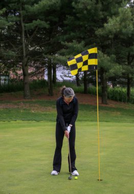 Golfçü açık havada güneşli bir öğleden sonra deliğin yakınında atış yapmaya odaklanıyor..