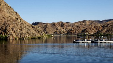 Arizona 'daki berrak gökyüzünün altında Colorado Nehri' nin sakin sularını yansıtan dağların manzarası..