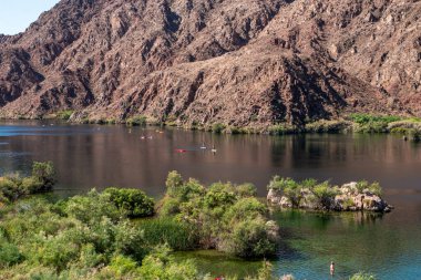 Kano grupları dağlarla çevrili sakin bir gölde huzur içinde kürek çekerler..