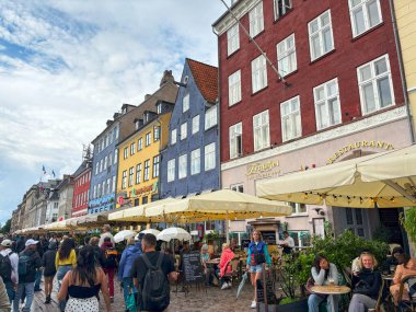 Nyhavn, Kopenhag, Danimarka - 2 Ağustos 2025: Kopenhag 'da canlı binalar ve açık hava oturma yerleri ile çevrili büyüleyici kanal.
