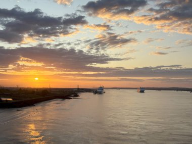 Gündoğumu, Tillbury İngiltere 'sindeki bir kanalda yavaşça sürüklenen gemiler gibi, suyun üzerinde sıcak bir parıltı yayar..