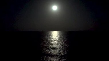 Parlak ay, huzurlu deniz yüzeyinde gece huzur dolu bir parıltı yayar.