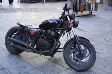 İstanbul, Türkiye - 27 Ekim 2022: Eski bir Harley Davidson İstanbul Kadıköy Caddesi 'nde park halindeydi. Arka planda, satış standında retro tarzı paltolar sergilendi..