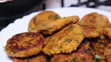 Kızarmış havuç topları bir tabakta tüttürüyor ve kızartma tavasında pişiriyor.