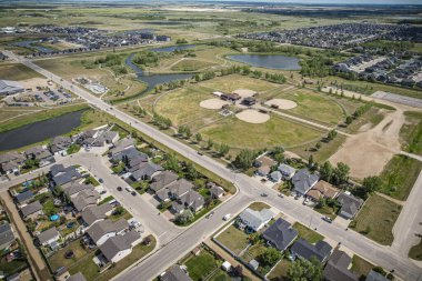Yaz mevsiminde Saskatchewan 'ın Martensville kentini görüntüleyen İHA görüntüsü, yemyeşil bölgeleriyle çevrili banliyö ve yerleşim alanlarını vurguluyor.