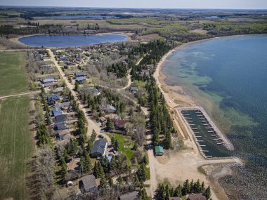 Saskatchewan, Iroquois Gölü 'ndeki Pebble Baye' in havadan çekilmiş bir fotoğrafı. Sahil şeridi, yemyeşil alanlar, göl kıyıları ve sakin yaz aylarında dinlenme alanları sergileniyor..