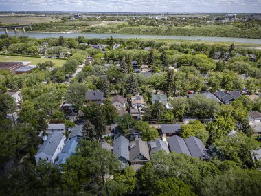 A high-resolution aerial drone photo of the City Park neighborhood in Saskatoon, Saskatchewan, showcasing tree-lined streets, historic homes, parks, and proximity to the South Saskatchewan River. clipart