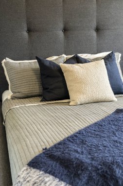 Mavi yorganı, beyaz ve mavi yastıkları olan bir yatak. Yastıklar rahat ve davetkar bir ortam yaratacak şekilde düzenlenmiş.