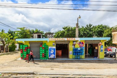 Ticari Hepa yazan bir tabelası olan küçük bir bina. Binanın önünden bir kadın geçiyor.