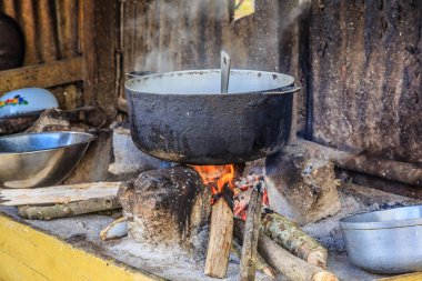 Bir tencere yemek ateşte pişiyor. Ateş sıcak, tencere siyah.