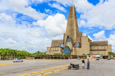 Çan kulesi ve büyük saat kulesi olan büyük bir bina. Bir adam ve bir kadın binanın önünde duruyorlar.