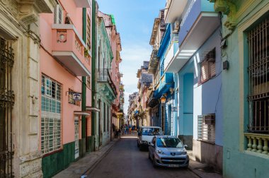 Kenarında mavi bir araba olan renkli bir cadde. Sokak binalarla dolu ve canlı bir atmosferi var.