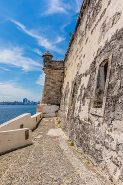 Okyanus manzaralı taş bir duvar. Duvar beyaz ve birkaç penceresi var.