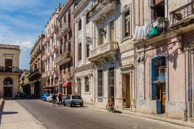 Eski ve yeni binaların karışımından oluşan bir şehirde bir sokak. Sokaklar arabalar ve motosikletle dolu. Binalar eski ve çok karakterli.