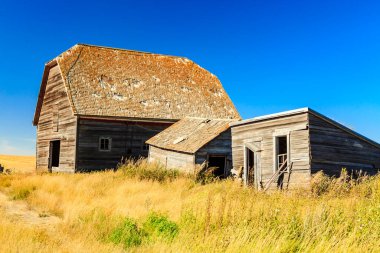 Eğik çatılı büyük, eski bir ahır bir tarlada oturur. Ahır kuru, sarı bir çim tarlasıyla çevrilidir. Ahır terk edilmiş ve bakımsız görünüyor.