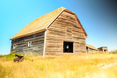 Önünde el arabası olan bir ahır. Ahır eski ve kırsal bir görünüme sahip. Görünürdeki tek nesneler ahır ve el arabası olduğu için manzara sakin ve sessiz.