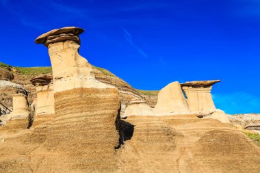 Üç küçük kaya oluşumuna sahip kayalık bir yamaç. Gökyüzü mavi ve berrak