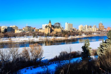 Altında nehir akan bir şehir ve arkasında büyük bir bina. Gökyüzü açık ve mavi