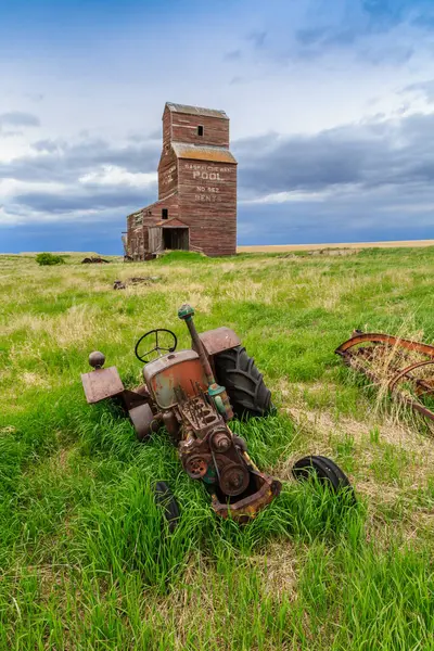 Eski bir traktör tahıl ambarının yanındaki tarlada oturuyor. Traktör paslanmış, silo eski ve terk edilmiş. Sahne sessiz ve huzurlu.