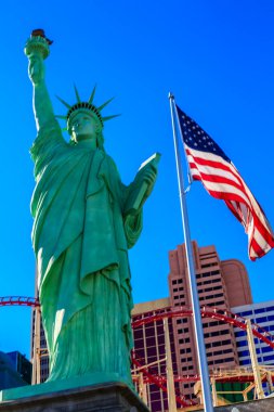 Elinde meşale ve bayrak tutan bir kadın heykeli binanın önünde duruyor. Bayrak, özgürlük ve vatanseverliğin sembolü olan Amerikan bayrağıdır. Heykel bir şehirde bulunuyor.