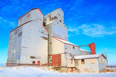 Büyük, eski bir tahıl ambarı karla çevrilidir. Bina kırsal bir alanda ve terk edilmiş. Gökyüzü açık ve mavidir, ve karla kaplı zemin manzaraya huzurlu, sakin bir atmosfer verir.
