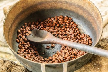 İçinde kaşık olan bir kase kahve çekirdeği. Kaşık tahtadan ve fasulyenin ortasında.
