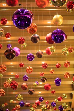 Tavandan sarkan renkli Noel süsleri. Renkler kırmızı, sarı ve mor.