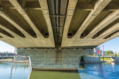 Altında beton bir yapı ve su yolu olan bir köprü. Köprü, su yolu boyunca uzanan büyük bir yapıdır.