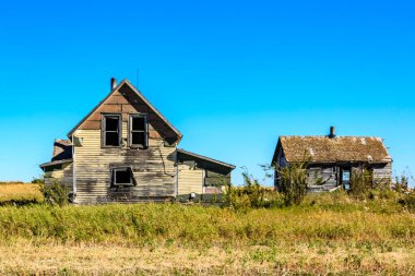 Üzerinde mavi bir gökyüzü olan bir tarlada küçük, eski bir ev oturuyor. Ev bakımsız durumda, birkaç penceresi tahtayla kapatılmış ve bir çatısı eksik. Sahne sessiz ve huzurlu.