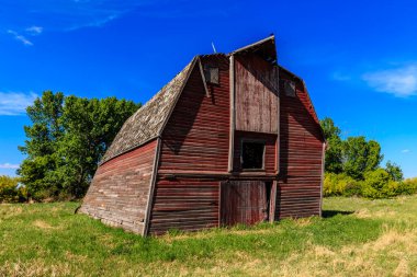 Çatı eğimli kırmızı bir ahır bir tarlada oturur. Ahır eski ve kırsal bir görünüme sahip. Gökyüzü açık ve mavi, çimenler yeşil ve gür. Ahır geçmişin bir sembolüdür.