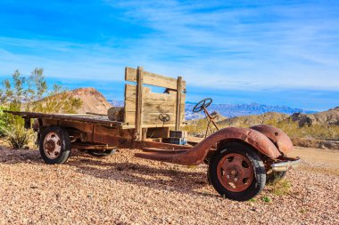 An old, rusted truck is parked on a rocky road. The truck is a vintage model and has a wooden bench on the back. The scene is quiet and peaceful, with the only sounds being the rustling of the wind clipart