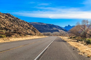 Üzerinde açık mavi gökyüzü olan bir yol. Yol boş ve üzerinde hiç araba yok.