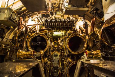 Bir geminin içi birçok büyük, parlak, altın renkli hoparlörlerle doludur. Oda loş bir şekilde aydınlatılmış, esrarengiz ve ürkütücü bir atmosfer sağlıyor.