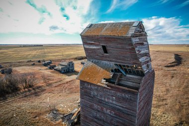 Eğik çatılı büyük bir tuğla bina bir tarlada. Bina terk edilmiş ve bakımsız görünüyor.