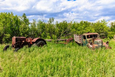 Eski bir traktör ve bir kamyon çim tarlasında oturuyorlar. Traktör paslanmış, kamyon da eski ve bozuk. Sahne terk edilmişlik ve ihmalkarlık hissi veriyor.