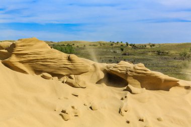 Geniş, kumlu bir çöl ortasında büyük bir kaya oluşumu var. Gökyüzü berrak ve bulutsuz. Huzurlu ve huzurlu bir atmosfer yaratıyor. Kayalar çöle saçılmış.