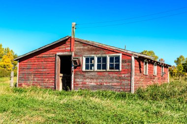 Bacası ve penceresi olan kırmızı bir ahır. Ahır eski ve kırsal bir görünüşü var.