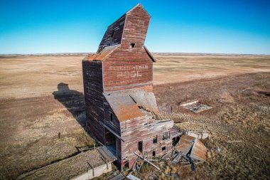 Yukarıdan büyük, eski, terk edilmiş bir bina görülüyor. Bina bir tahıl ambarı ve geniş, boş bir araziyle çevrili. Gökyüzü açık ve mavidir ve güneş ışıl ışıl parlar.
